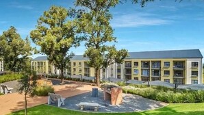 Hotel de varios pisos con un patio que incluye asientos exteriores y árboles.