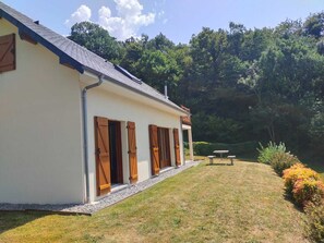 A single-story building with a sloped roof, a gravel pathway leading to the entrance, and a small outdoor seating area. - Family home in the mountains, in the Ossau Valley (Béost) (Béost)