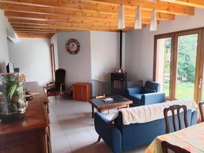 A cozy living room with a wooden ceiling, a fireplace, a dining area, and a large window. - Family home in the mountains, in the Ossau Valley (Béost) (Béost)