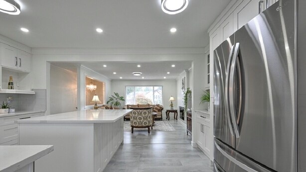 A modern kitchen with a large island, stainless steel appliances, and recessed ceiling lighting. - Fully Furnished House, Delta, BC, Canada, (Delta)