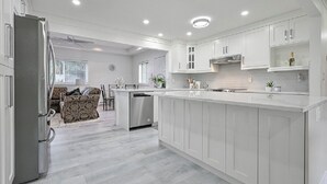 A modern kitchen with white cabinetry, a central island, and recessed ceiling lights. - Fully Furnished House, Delta, BC, Canada, (Delta)