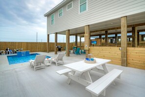 Ein Außenpoolbereich mit Holzterrasse, weißen Picknicktischen und Liegestühlen.