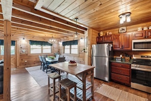 Ein Holzblockhaus-Interieur mit Essbereich, Küche und großen Fenstern.