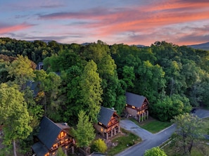 Eine Lodge mit mehreren Blockhütten, umgeben von dichtem Wald, erreichbar über eine asphaltierte Straße.