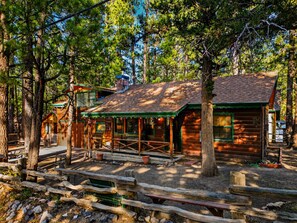 Ein rustikales Blockhaus mit Veranda, umgeben von Bäumen.