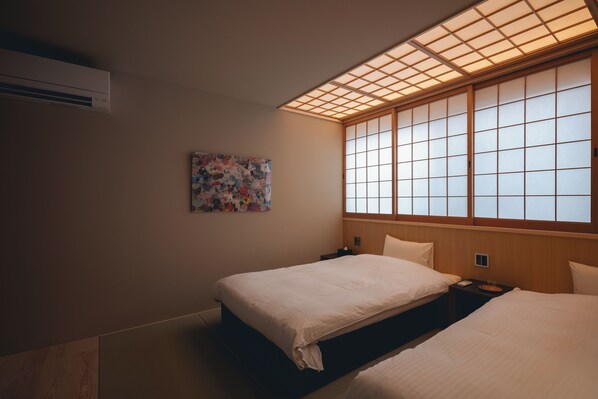 A hotel room with two beds, a large window with wooden frames, a wall-mounted air conditioner, and a colorful abstract painting. - Experience Ise Miyamachi Hotel (Ise)