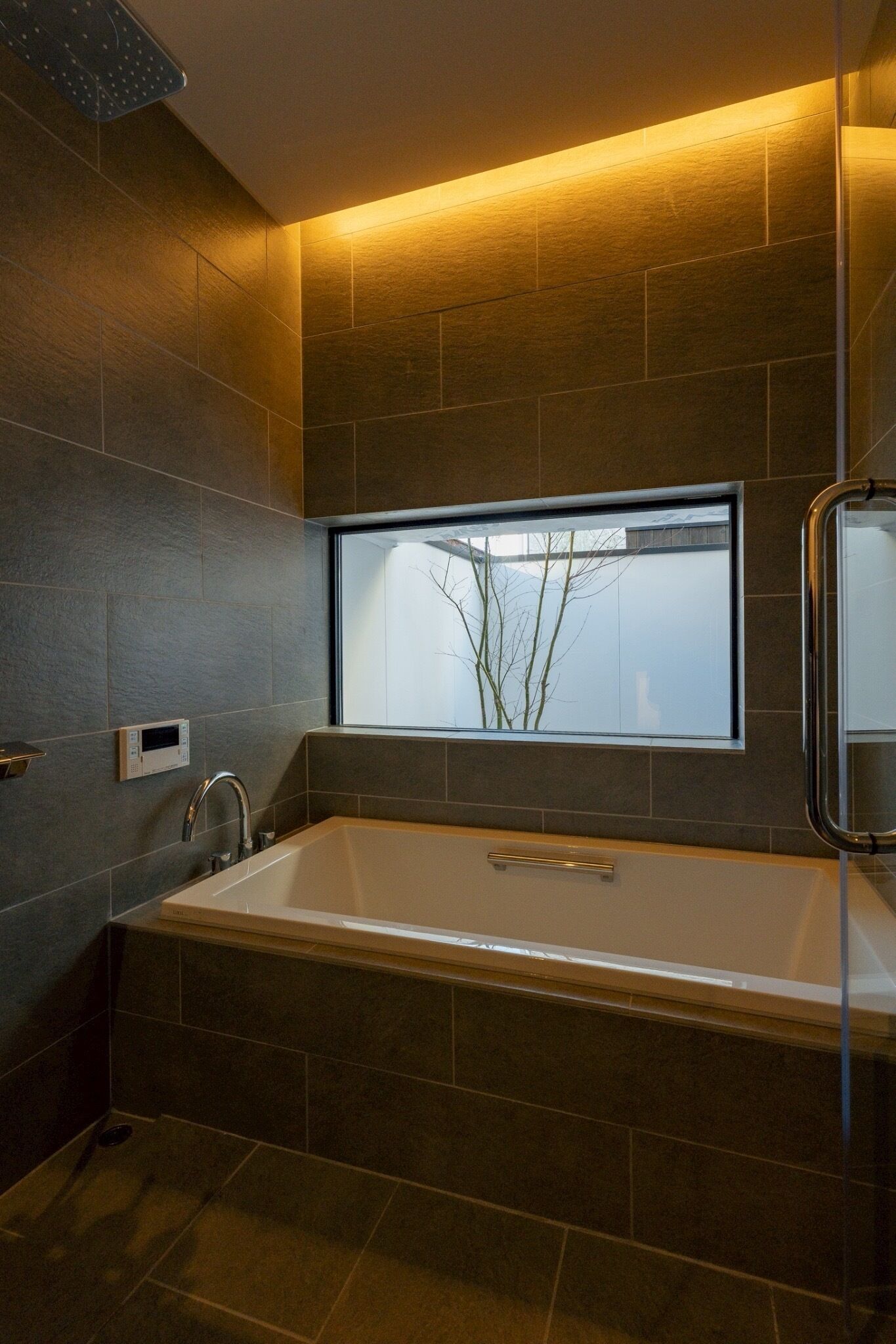 Un baño moderno con bañera, ventana y cabezal de ducha.
