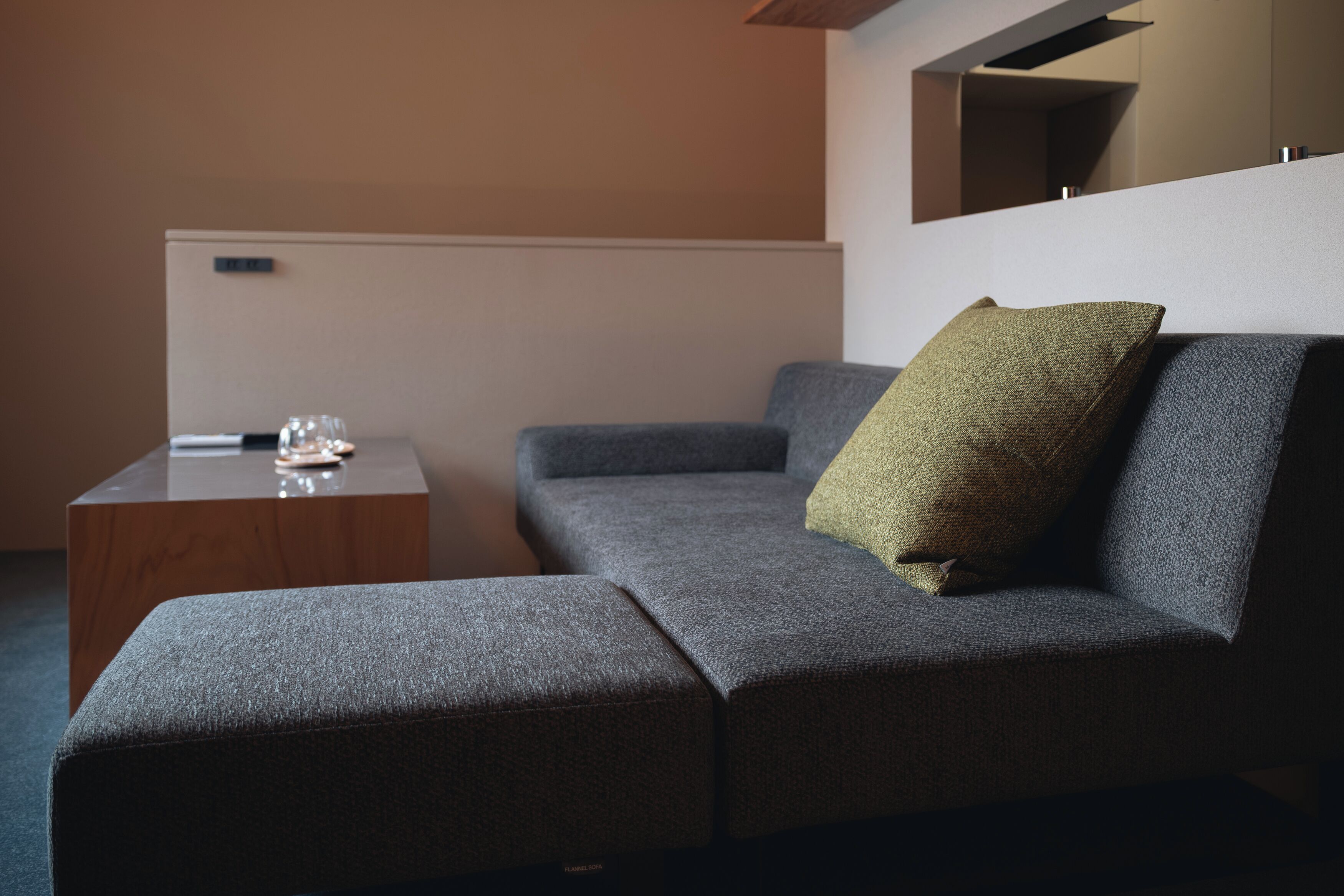 Una sala de estar moderna con un sofá gris, una mesa de centro de madera y una almohada verde.
