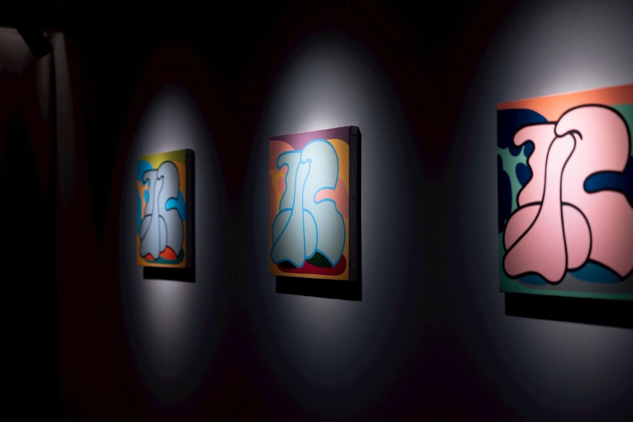 Three illuminated wall art pieces with abstract designs.