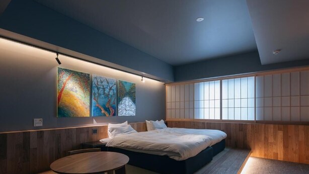 A modern bedroom with a bed, a wooden table, and artwork on the wall.