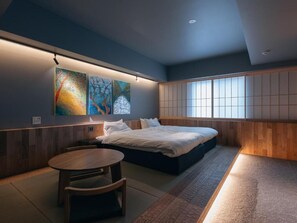 Un dormitorio moderno con una cama, una mesa de madera y obras de arte en la pared.