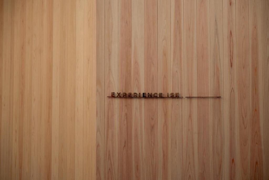 Un mur en bois sur lequel est gravée l’inscription : « L’EXPÉRIENCE, C’EST… ».