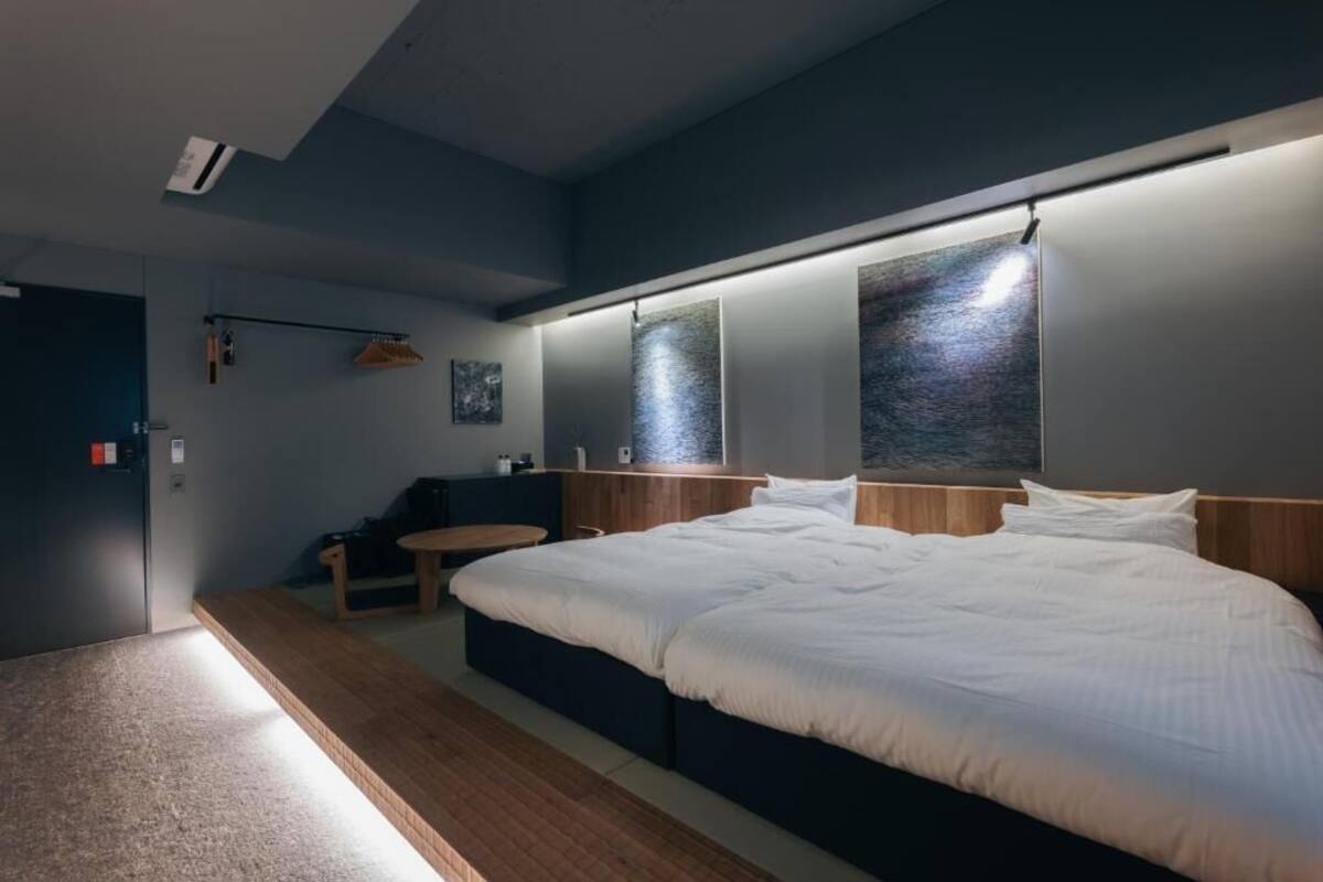 Ein modernes Schlafzimmer mit einem großen Bett, Nachttischen, einer Bank und einer Wandleuchte.