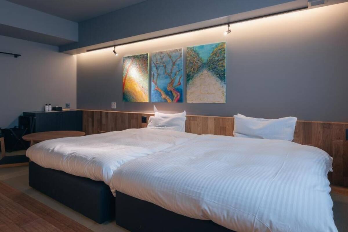 Ein modernes Hotelzimmer mit einem großen Bett, einem Holz-Kopfteil und einem Schreibtisch mit Stuhl.