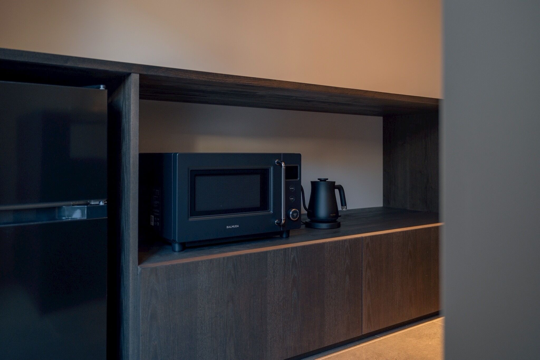 A kitchen area with a microwave and a coffee maker on a wooden shelf.