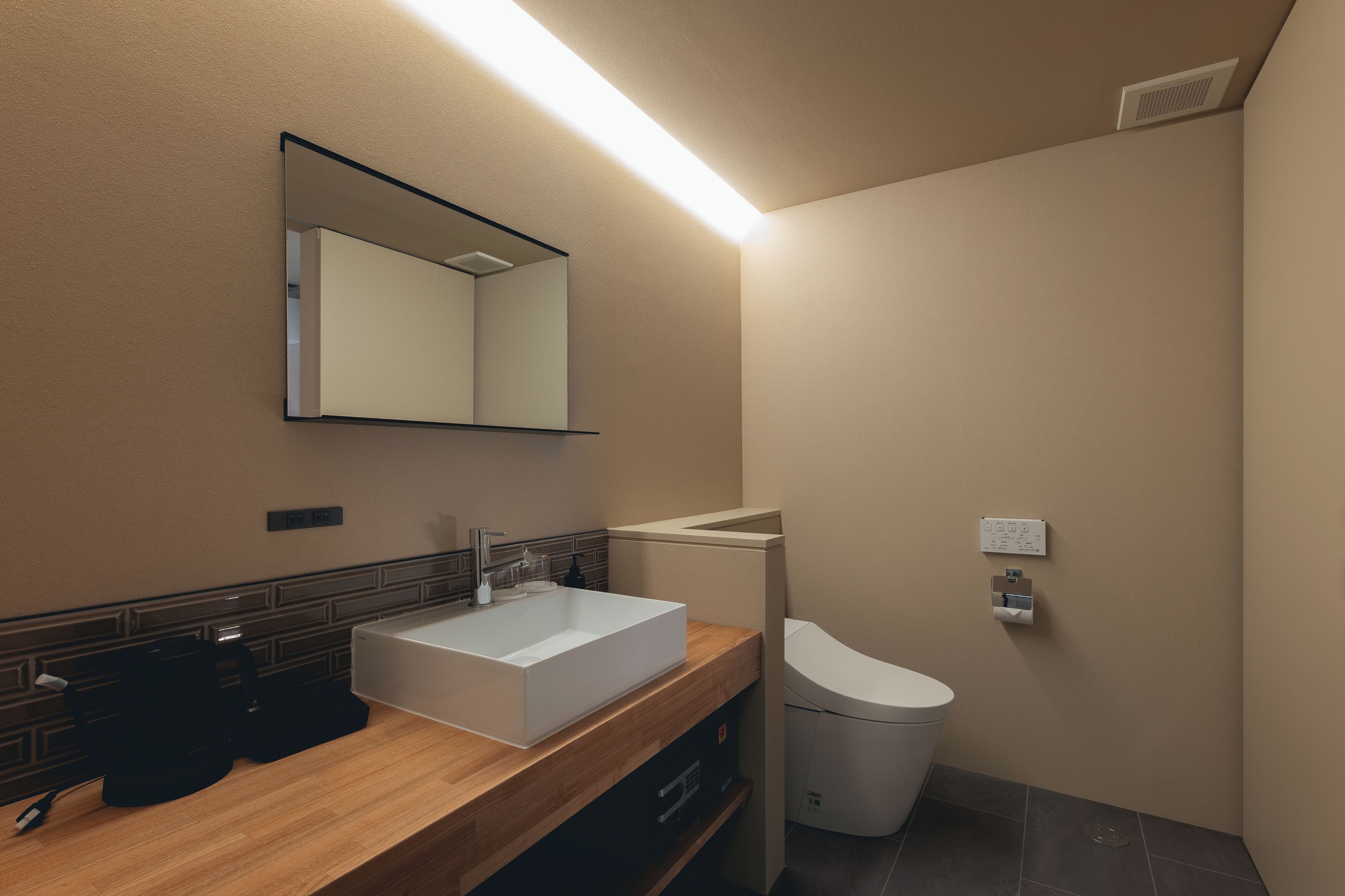 A modern bathroom with a large mirror, a white sink, and a toilet.