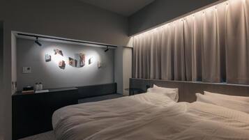 A modern bedroom with a bed, a bedside table, a wall-mounted artwork, and a window with curtains.
