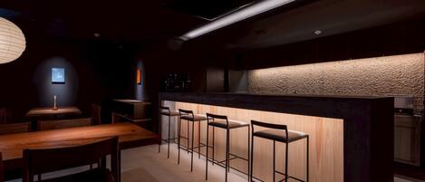 Uma área de bar moderna com banquetas de madeira, um balcão e uma parede com textura diferenciada.