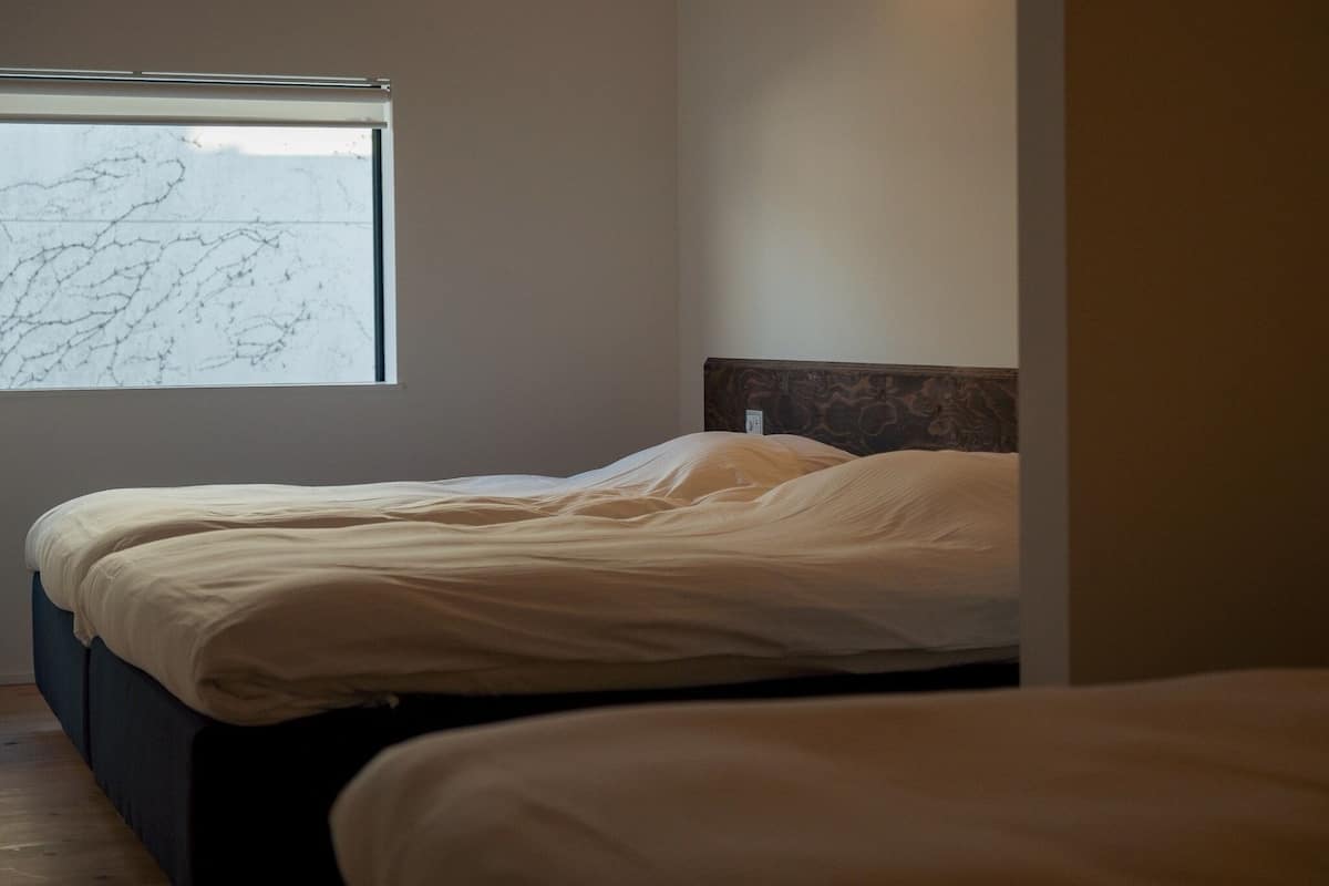 Ein Schlafzimmer mit zwei Betten, einem Fenster mit Aussicht und einem Kopfteil mit Musterdesign.