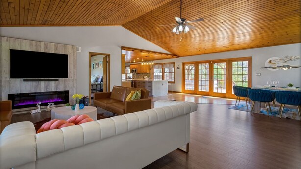 A spacious living area with a fireplace, a television, a sofa, and a dining area with chairs.