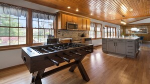 A spacious kitchen with wooden cabinets, a foosball table, and a large island with a sink.