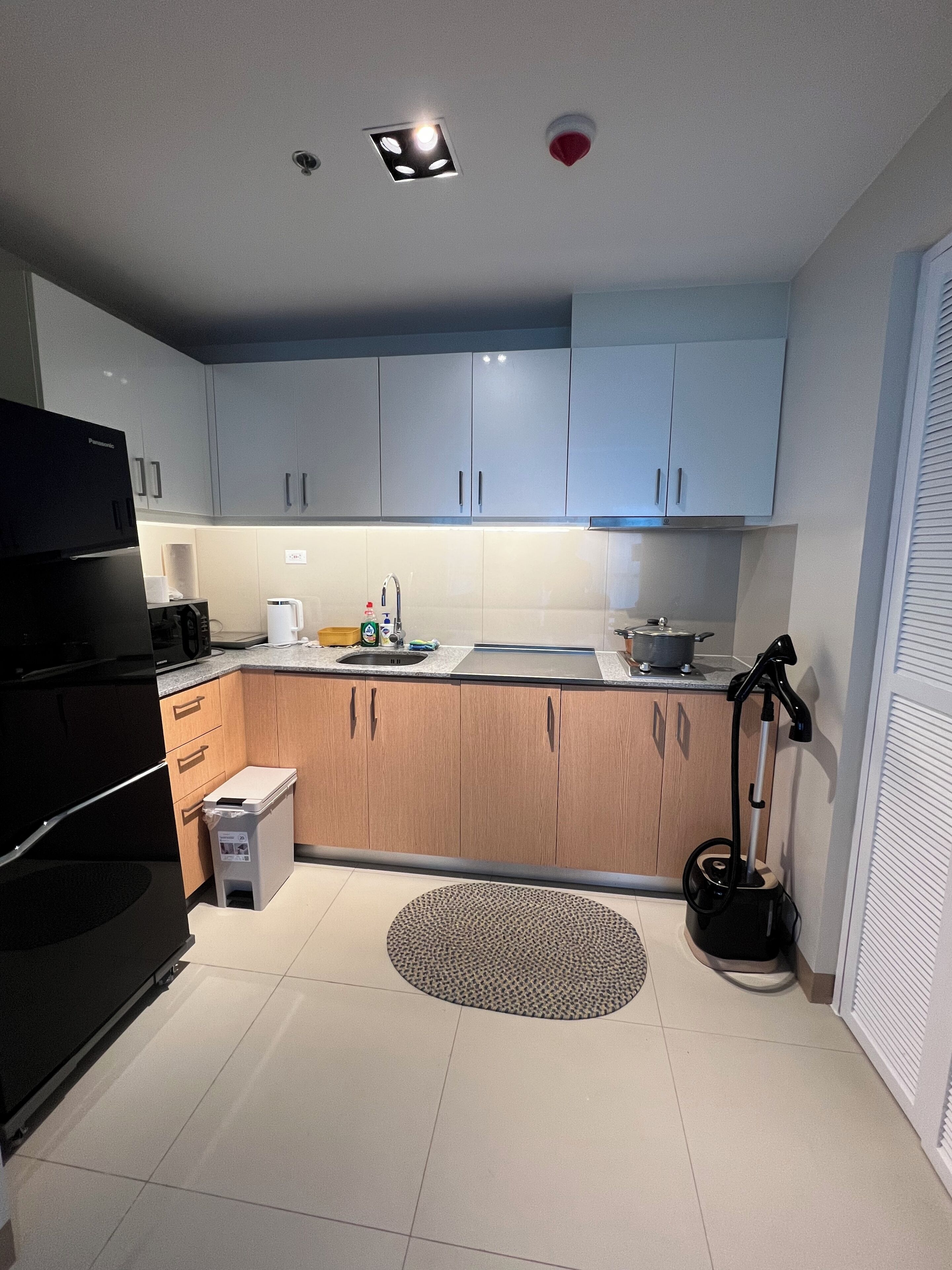 A modern kitchen with light-colored cabinets, a black refrigerator, a sink, and a coffee maker.