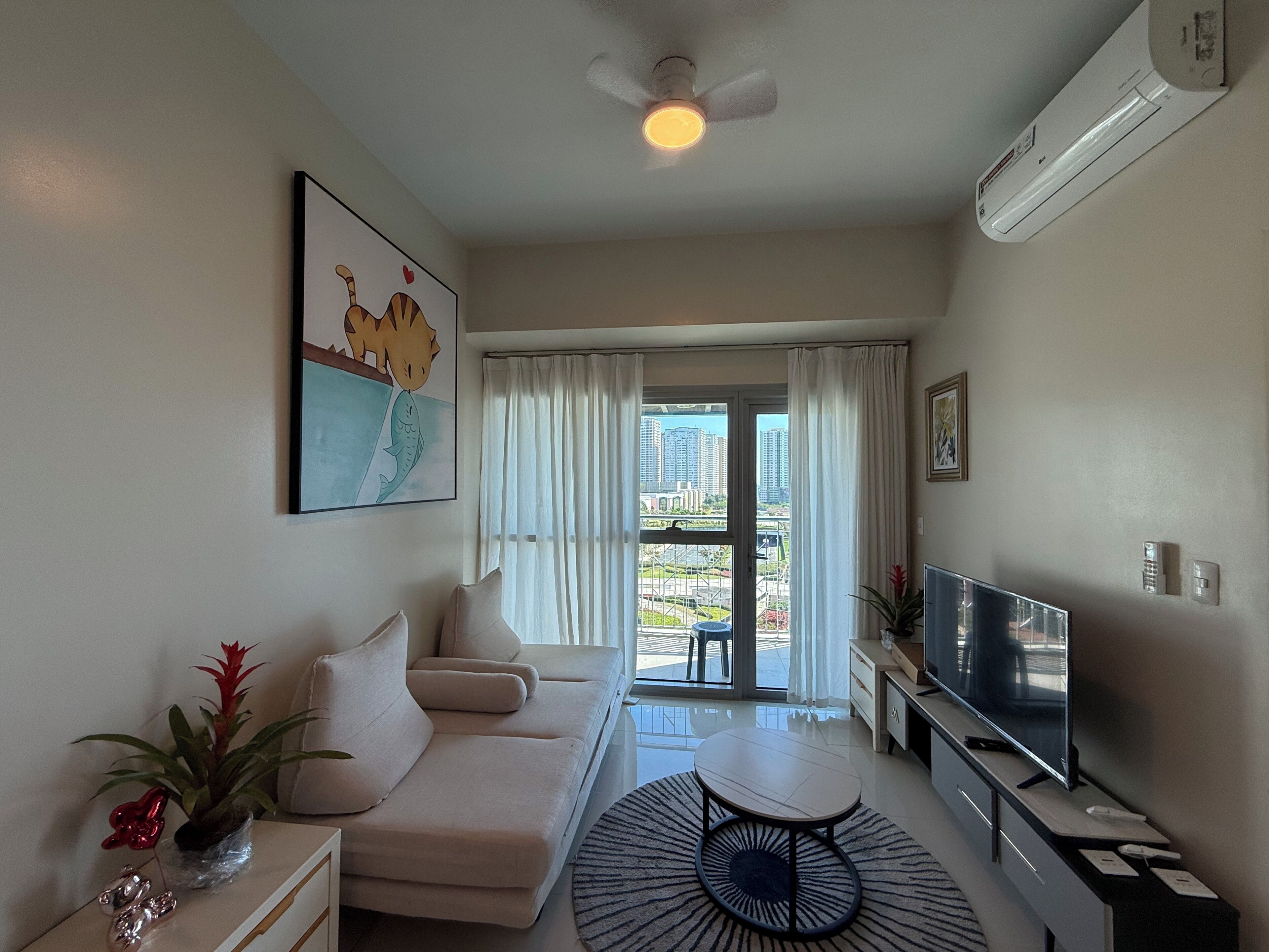 A modern living room with a sofa, TV, and a view of the city through large windows.