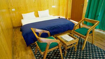 Ein Zimmer mit einem Bett, zwei Stühlen, einem kleinen Tisch und einem gemusterten Teppich.