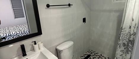A bathroom with a white sink, toilet, and shower area.