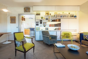 Ein Wohnzimmer mit Essbereich, einer Küche und einem Bücherregal voller Bücher und Dekoration.