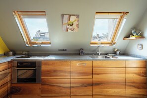 Eine Küche mit Holzausstattung, einem Backofen, einer Spüle und Dachfenstern.