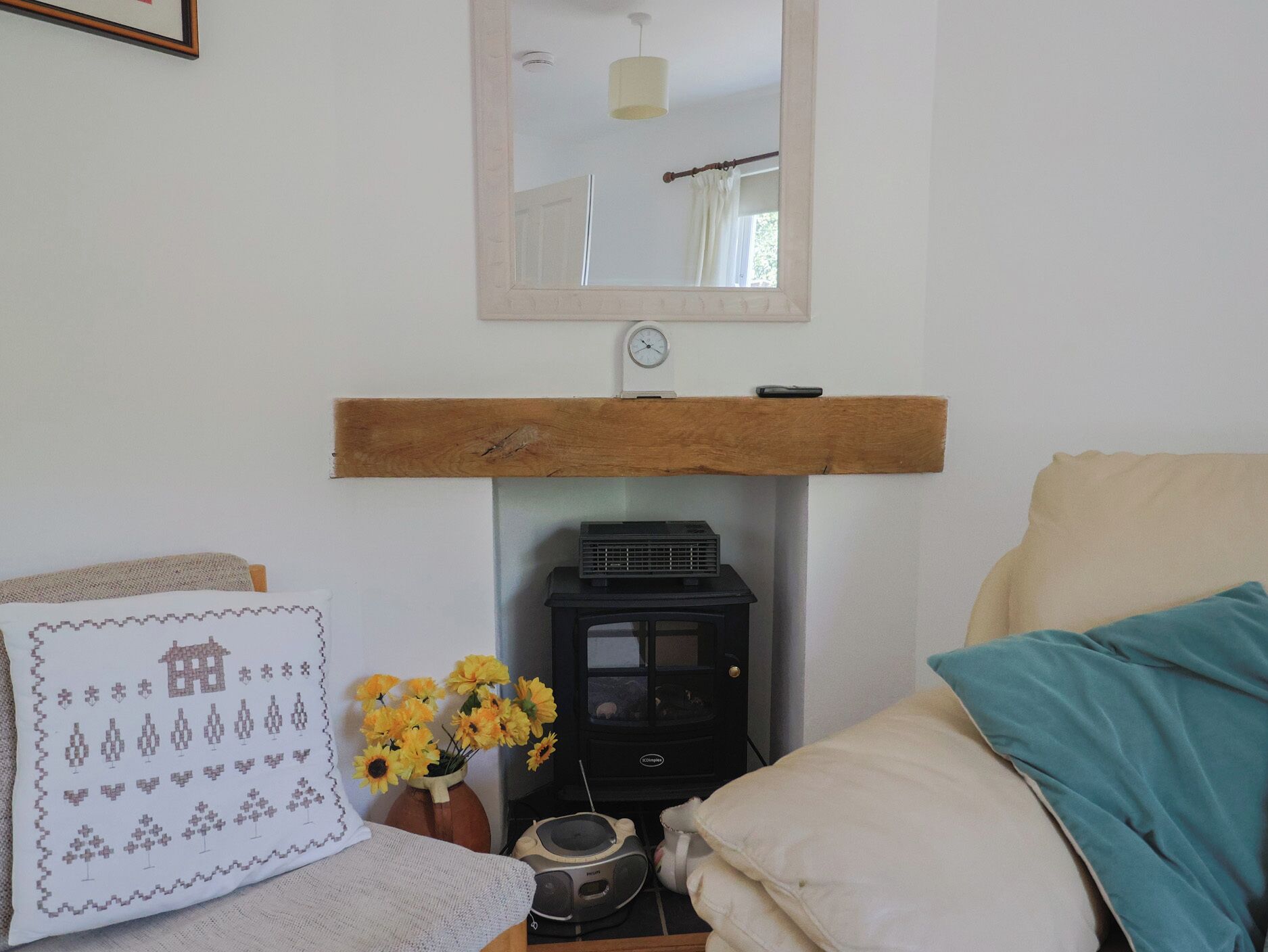 Une pièce confortable avec un lit, une étagère en bois, un radiateur, une horloge et un vase rempli de fleurs.