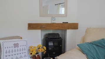 A cozy room with a bed, a wooden shelf, a heater, a clock, and a vase with flowers.