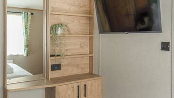 Ein Holzkabinett mit Spiegel, ein an der Wand montierter Fernseher und eine Steckdose.
