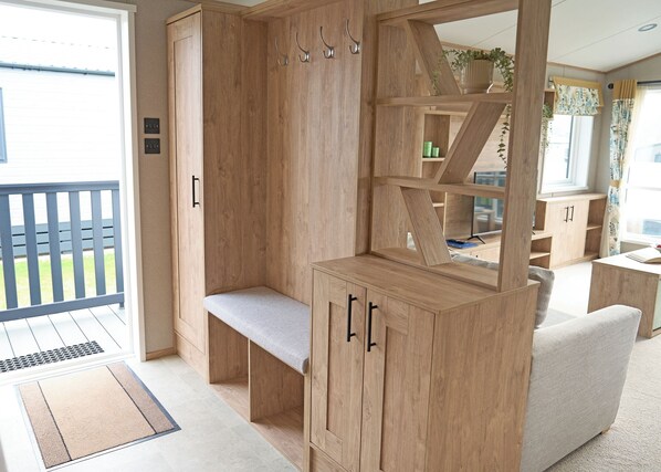 A wooden room with a bench, shelves, and a view of the outdoors.