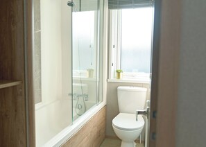 Ein Badezimmer mit Duschkabine, Toilette und einem Fenster mit Blick.
