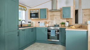 Une cuisine avec des armoires de couleur turquoise, un four en acier inoxydable et un four à micro-ondes.