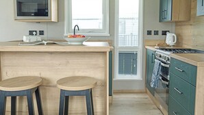 A kitchen with a central island, two stools, a microwave, and a stove. - 3 bedroom accommodation in Landford, Nr Salisbury (Landford, Nr Salisbury)