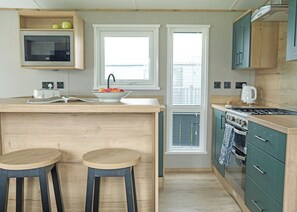 A kitchen with a central island, two stools, a microwave, and a stove. - 3 bedroom accommodation in Landford, Nr Salisbury (Landford, Nr Salisbury)