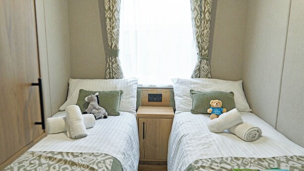 A double bed room with two single beds, a bedside table, a power outlet, and a window with curtains. - 3 bedroom accommodation in Landford, Nr Salisbury (Landford, Nr Salisbury)