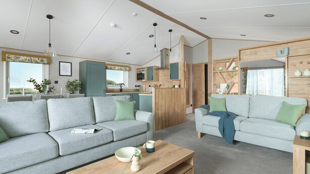 Een moderne woonkamer met een bank, een salontafel en een keuken met houten kasten.