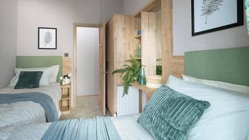 A bedroom with two beds, a wooden wardrobe, a radiator, and a framed leaf artwork.