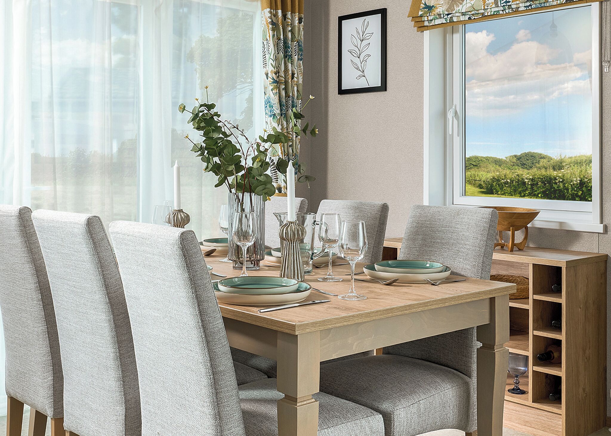 A dining area with a wooden table, grey upholstered chairs, and a vase with greenery.