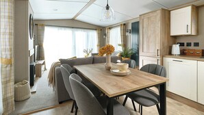 Una cocina moderna con una mesa de comedor de madera, sillas grises y una lámpara colgante.