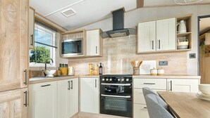 Una cocina moderna con armarios blancos, horno empotrado, microondas y un comedor con mesa y sillas.