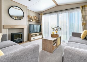 A modern living room with a fireplace, television, and comfortable seating. - 2 bedroom accommodation in Great Yarmouth (Great Yarmouth)