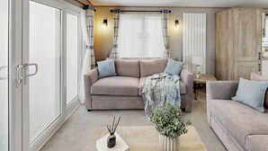 Ett modernt vardagsrum med en soffa, ett soffbord, en lampa och en krukväxt.