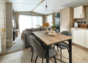 Eine moderne Küche mit einem Holztisch, grau gepolsterten Stühlen und einer hängenden Pendelleuchte.