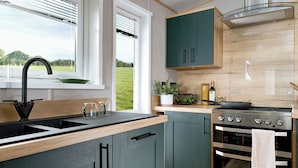 Una cucina moderna con lavello, piano cottura e mobili verdi.