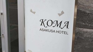 L’entrée d’un hôtel, avec une enseigne indiquant « KOMA ASAKUSA HOTEL » et des motifs décoratifs.